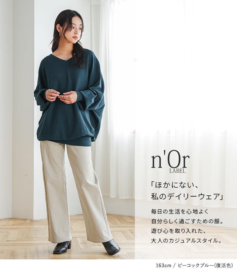 復活色ピーコックブルーのドルマン綿ニットにベージュパンツをあわせたスタイル。深みのある知的カラーとゆったりシルエットが、大人の日常着に品格とこなれ感を与えます。
