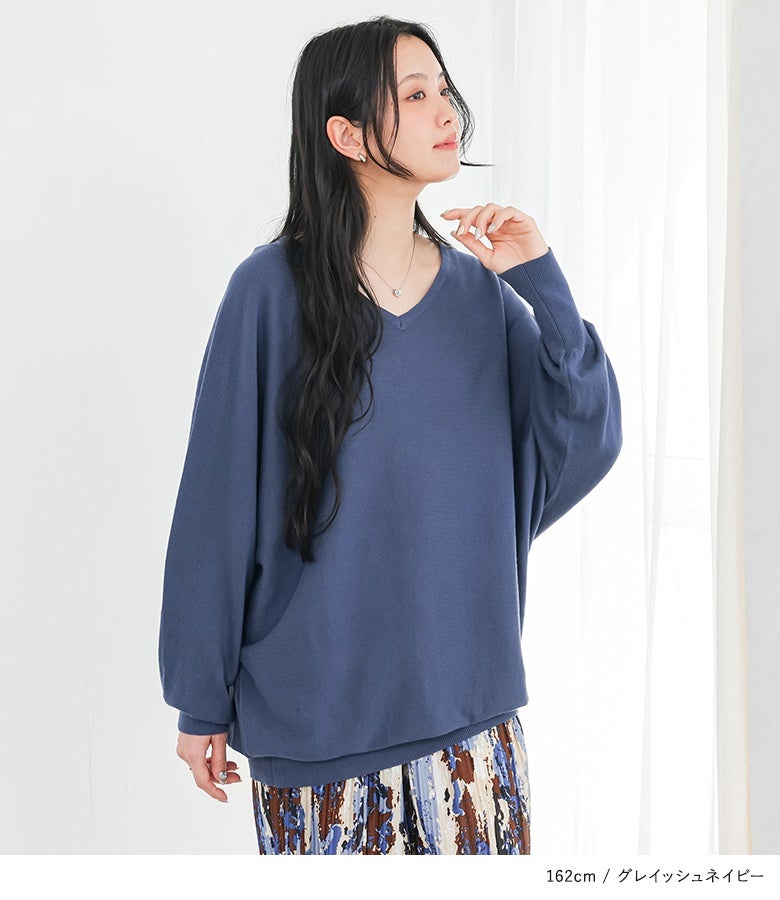 グレイッシュネイビーのドルマン綿ニット。デコルテを美しく魅せる上品なVネックと、手元や裾にフィットする長めのリブ使いが、ゆったりとした着心地の中にメリハリのあるラインを作ります。