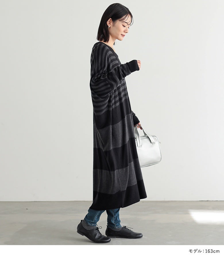 ブラック×グレーのボーダー柄ニットワンピースに細身デニムパンツと黒革靴を効かせた休日のおでかけスタイル。サイドから見ても美しいドレープ感がこなれた印象を与えます。