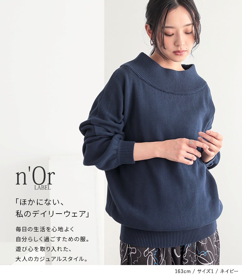 ネイビーのドロップショルダー綿ニットに総柄フレアパンツを合わせた、個性的で遊び心を取り入れた大人のリラックスコーデ。