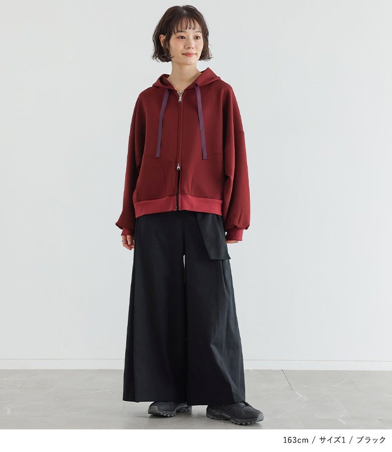ブラックのベルトカシュクールワイドパンツにジップパーカーとスニーカーを合わせた大人のスタイリング。ウエストの重なりデザインがアクセントとなり、好印象でスポーティーな着こなしに決まります。