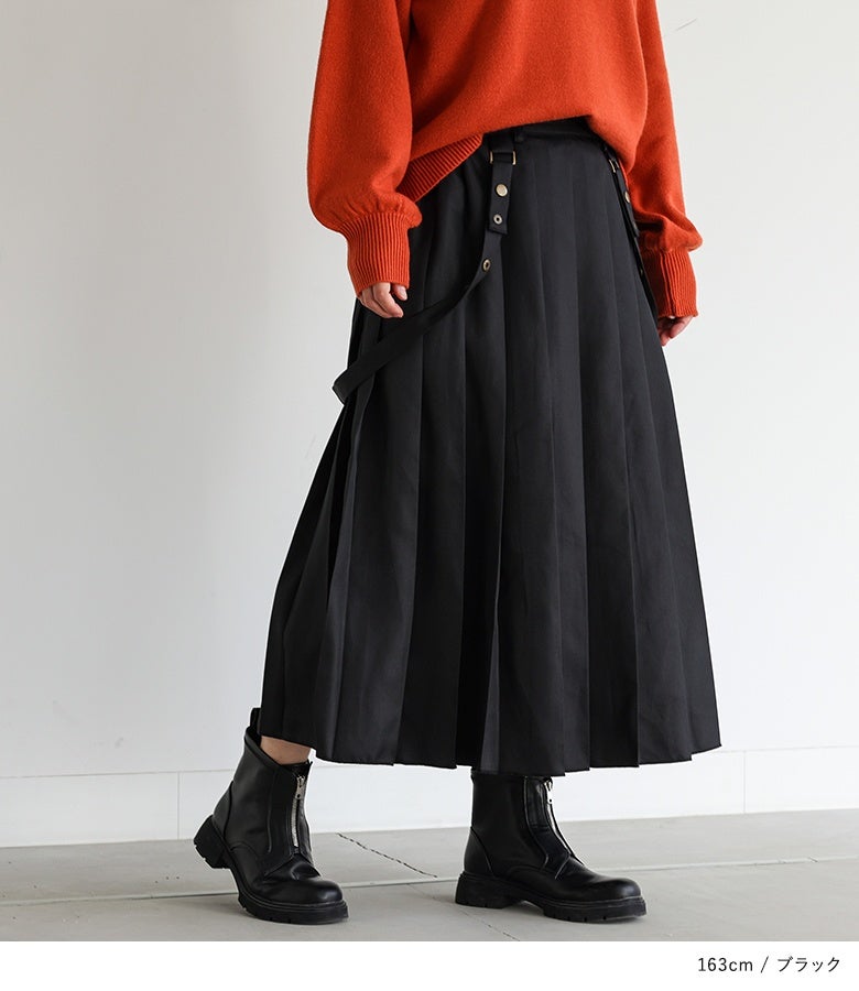 黒のロングプリーツスカートにオレンジのモックネックニットと黒ブーツを合わせた、華やかさとシックさを兼ね備えた秋冬のデートお出かけコーデ。