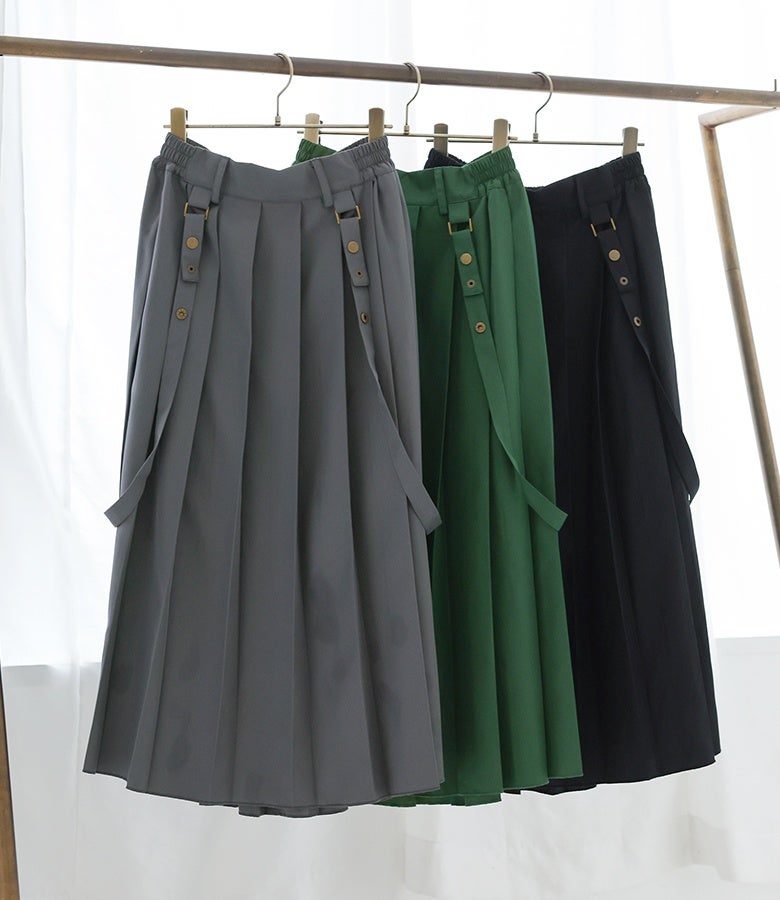 グレー、アンティークグリーン、ブラックの全3色展開。サスペンダーの付け外しで印象を変えられる、ハンガーにかかったサス付きプリーツスカート。