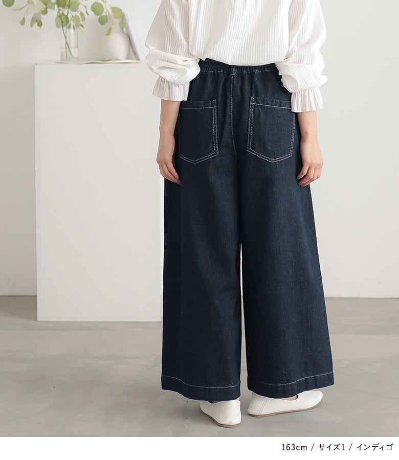 インディゴのワイドデニムパンツ。後ろウエストのゴム仕様が心地よいフィット感を提供しつつ、ヒップ周りの大きめポケットがバックスタイルをすっきり見せて体型カバーに貢献します。