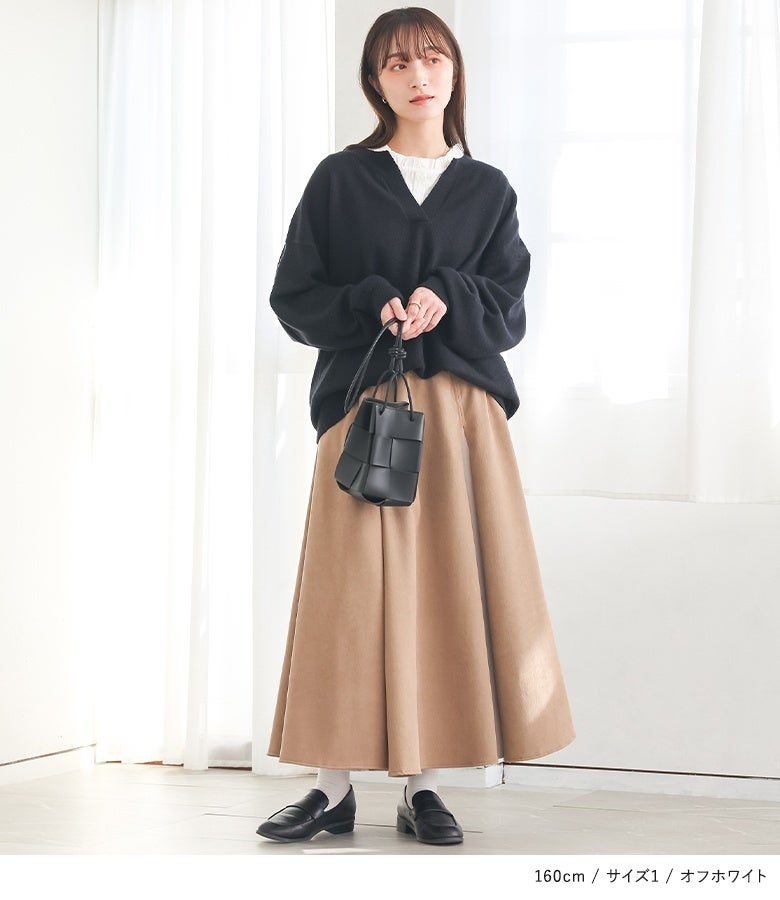 オフホワイトのフリル襟タンクトップに黒のキーネックニットとベージュスカートをあわせた洗練スタイル。胸元から覗く繊細なフリルが、大人っぽいシックな装いに柔らかで華やかなアクセントを与えます。