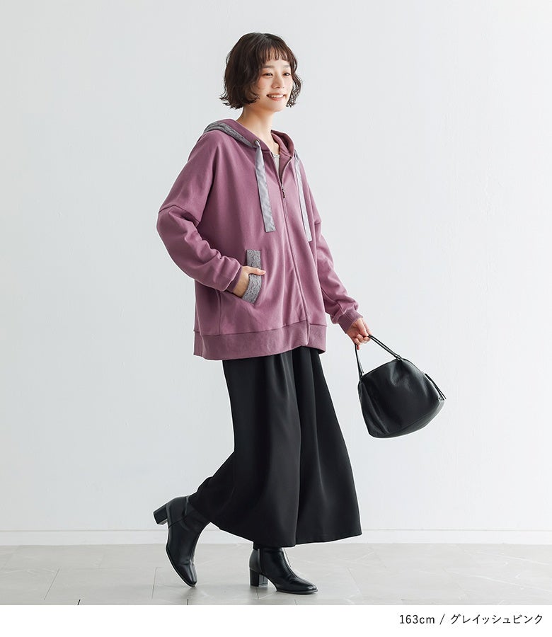 グレイッシュピンクのジップパーカーに黒のワイドパンツを合わせた着こなし。華やかなピンクとシックな黒ボトムが引き締め合い、こなれたモードカジュアルを演出します。