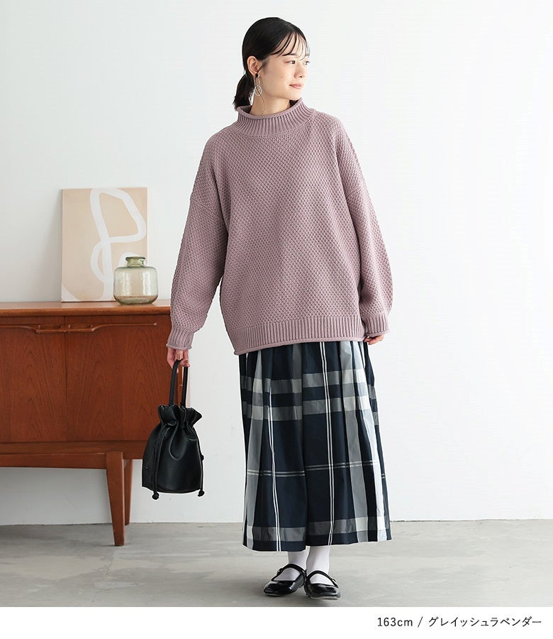 グレイッシュラベンダーのかのこ編みハイネックニット。くすみ感のある絶妙なラベンダーカラーとゆとりのあるシルエットが、チェック柄ロングスカートとあわせた大人上品な着こなしを引き立てます。