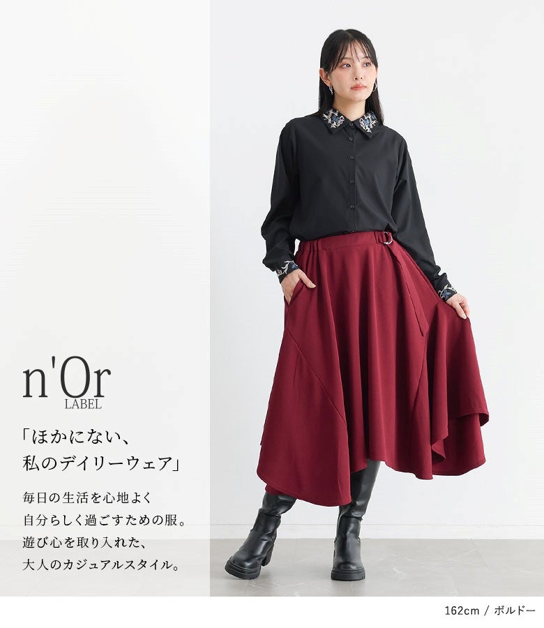 ボルドーのヘムラインフレアスカートに黒シャツを合わせた華やかな着こなし。ウエストのベルトアクセントと動きのある切り替えラインが、シンプルなワンツーコーデをシックに格上げします。