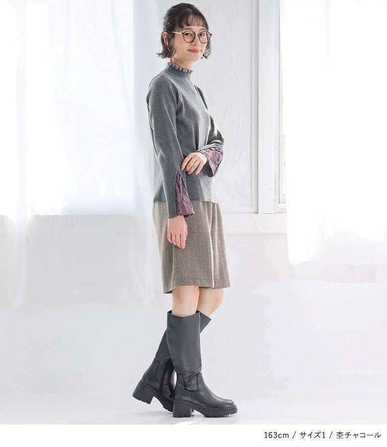 杢チャコールのドッキングレースリブニットにチェック柄ショートパンツと黒のロングブーツを合わせたトレンド感あふれる秋冬お出かけコーデ。