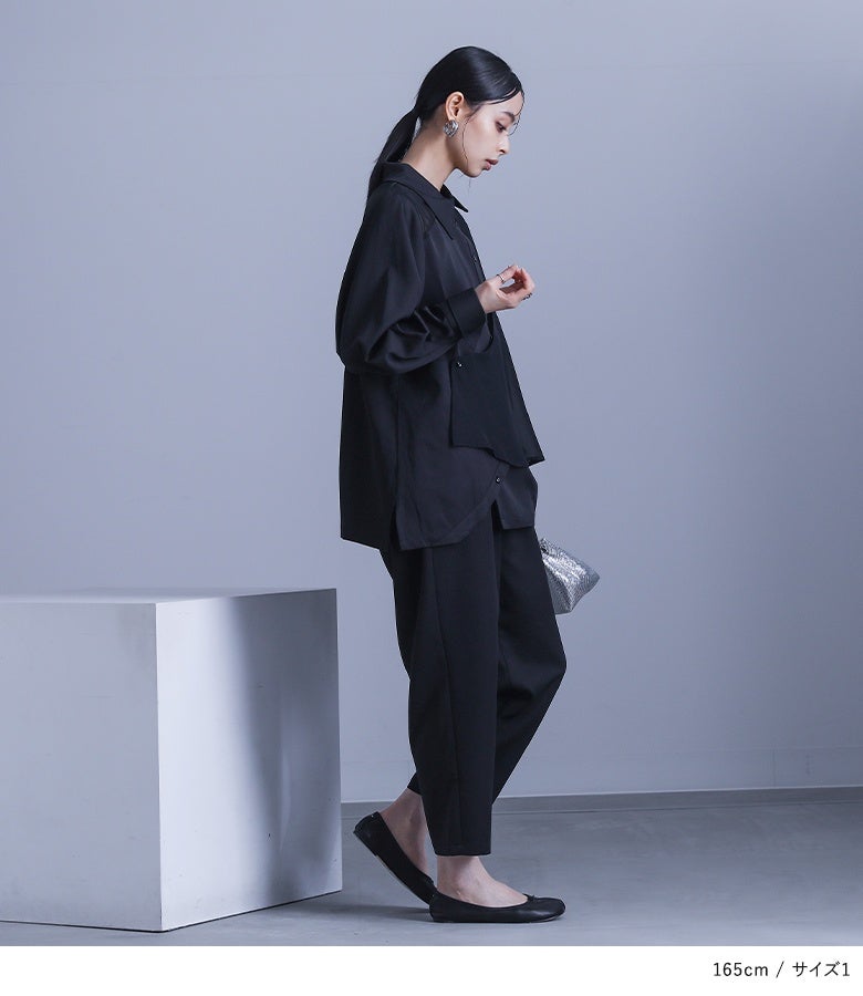 ブラックのシフォンジレ付きシャツセットアップ。サイドから見ても流れるようなアシメ丈ラインが美しく、すっきりとしたパンツフォルムと合わさることで横姿まで洗練されたモードな印象を与えます。