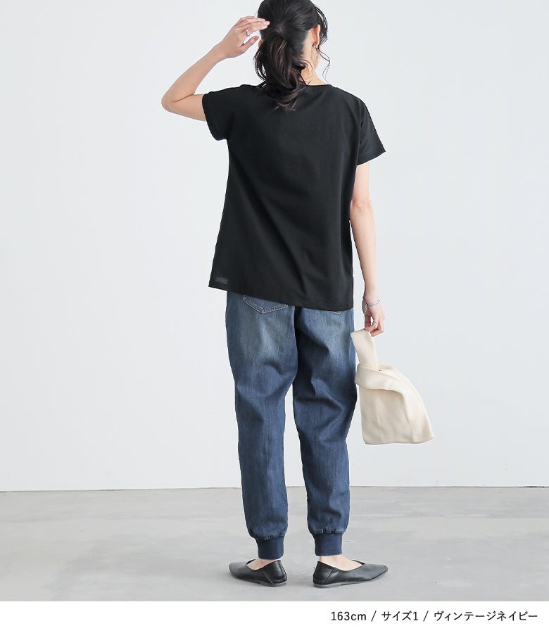 ヴィンテージネイビーのデニムジョガーパンツに黒のTシャツ、白いバッグを合わせたカジュアルスタイル。ヒップ周りはゆったりと、足首に向かって細くなる美脚テーパードラインがすっきりとした佇まいを演出します。