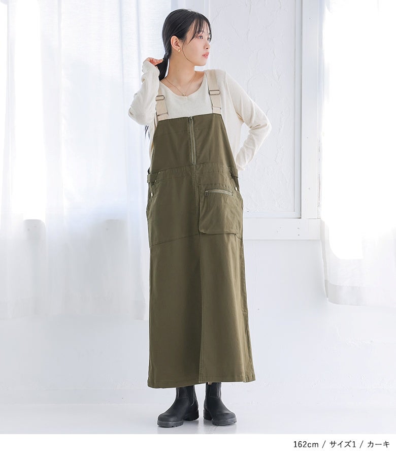 カーキのジャンパースカートに白カットソーを合わせた大人の着こなし。縦長ラインを強調するフロントジップとスマートなAラインフォルムが、スタイルアップ効果を発揮します。