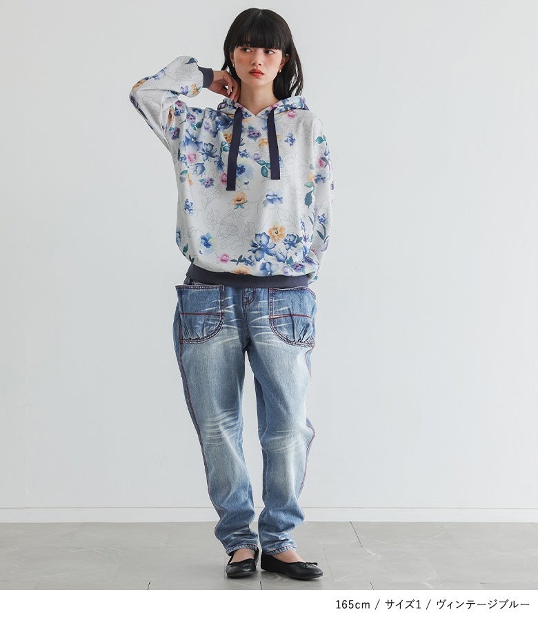 ヴィンテージブルーの赤ステッチ赤ジップサルエルデニムパンツ。花柄の総柄パーカーと合わせたスタイリングで、ラフでありながら洗練された大人カジュアルを完成させます。