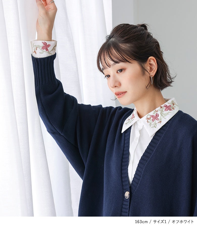 オフホワイトの花刺繍シャツにネイビーのVネックカーディガンを重ねたスタイル。Vネックの胸元や袖口のリブから覗くピンクの花刺繍がアクセントとなり、手元や顔周りを華やかに魅せてくれます。
