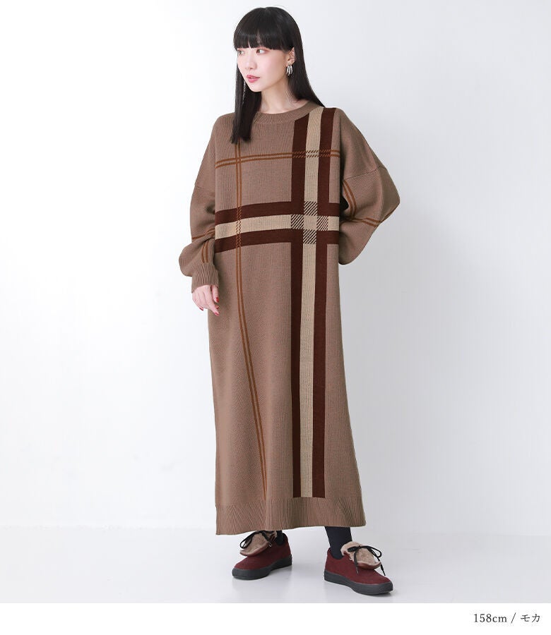 モカのチェックジャカードニットワンピース。全身を優しく包み込むゆったりとしたロングシルエットと落ち着いたブラウン調のチェック柄が、秋の装いに上品なこなれ感を演出します。