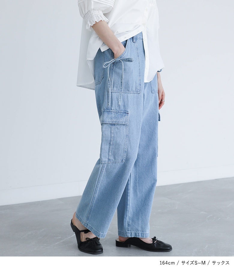 サイドリボンカーゴデニムパンツ。広がりを抑えたストレートなワイドシルエットが縦ラインを美しく強調し、サックスの軽やかなカラーと足元のミュールが爽やかでこなれた横姿を完成させます。