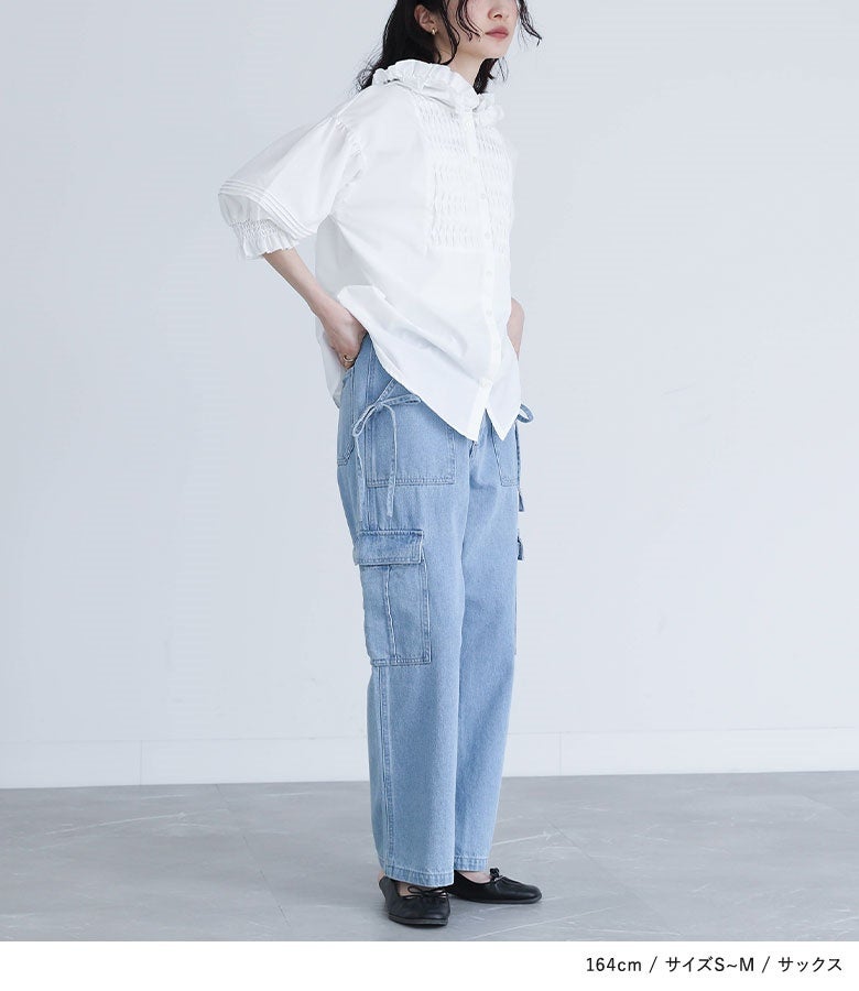 サックスのサイドリボンカーゴデニムパンツ。すっきり見えを叶えるストレートラインとサイドのポケットデザインが、ブラウスと合わせた立ち姿をスマートかつ洗練された印象へ導いてくれます。