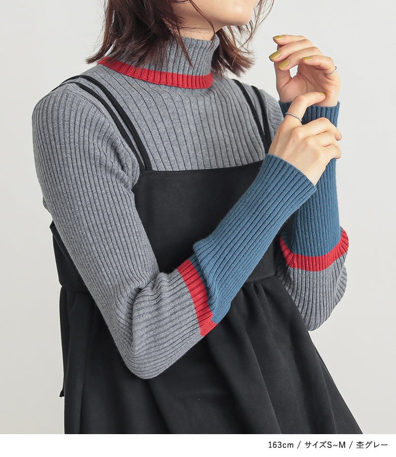杢グレーの袖配色リブニット。程よく立ち上がるハイネックと袖口のバイカラー切り替えが、シンプルなレイヤードスタイルに洗練されたアクセントを与えます。