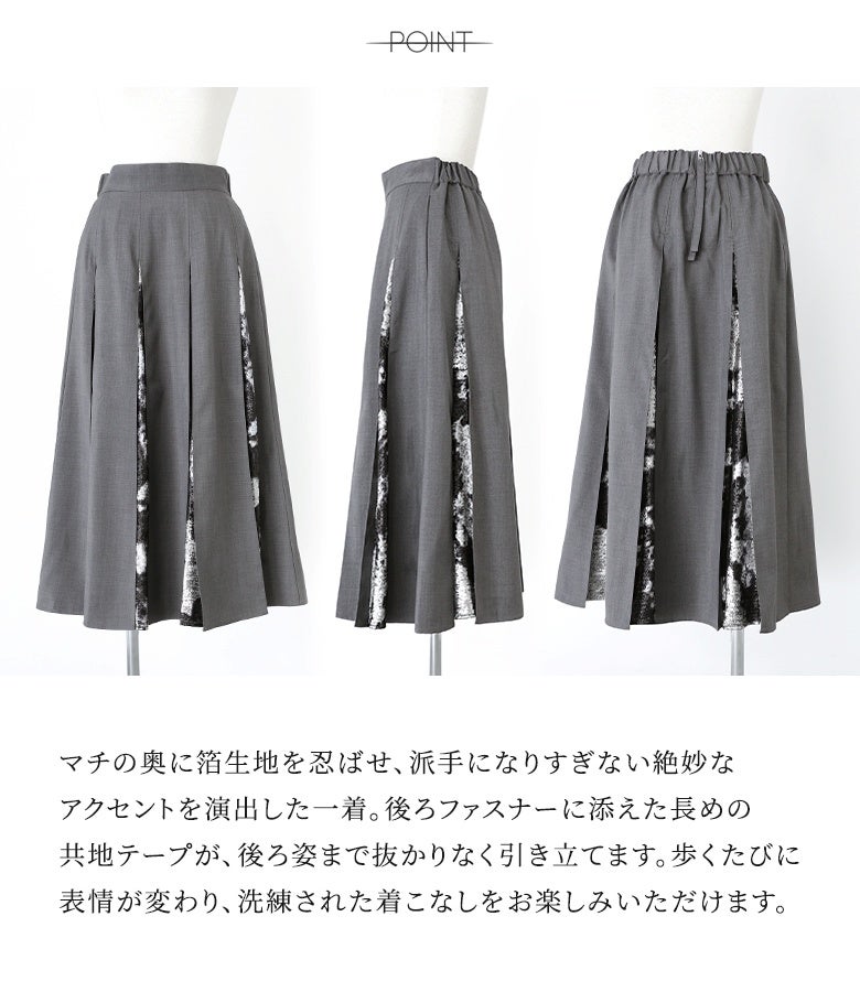 マチの奥に箔生地を忍ばせ、派手になりすぎない絶妙なアクセントを演出した一着。後ろファスナーに添えた長めの共地テープが、後ろ姿まで抜かりなく引き立ててくれます。