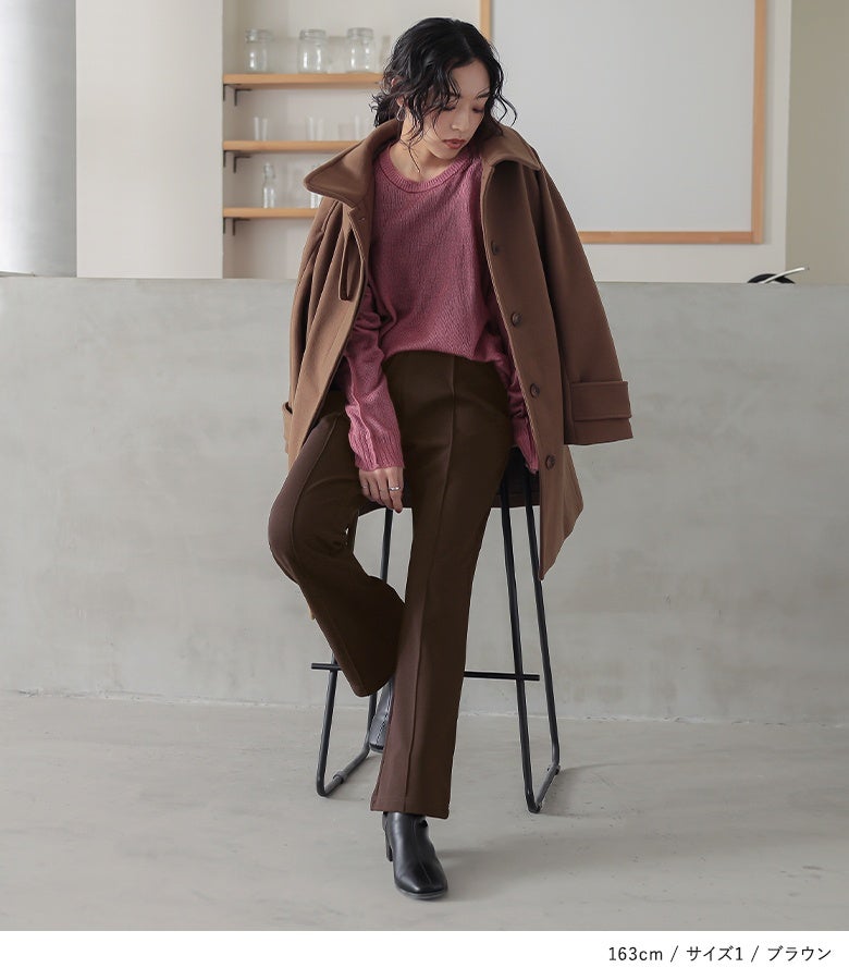 ブラウンの裏起毛フレアパンツ。深みのあるブラウンにピンクの透かし編みニットとキャメルのコートを羽織った、温もりと洗練感が漂う秋冬のきれいめスタイルです。