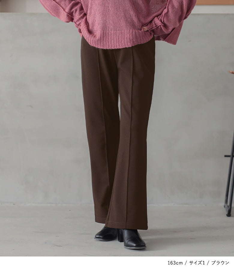 ブラウンの裏起毛フレアパンツ。縦のラインを強調するセンターピンタックが、ピンクのニットと合わせた着こなしにメリハリを与え脚長効果を際立たせます。