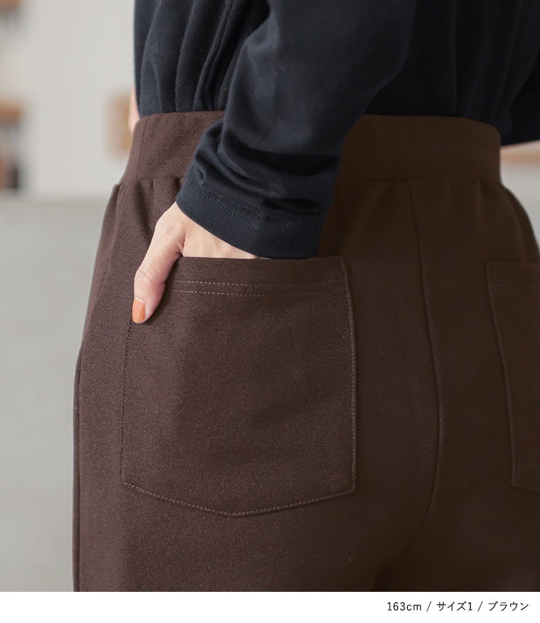 ブラウンの裏起毛フレアパンツ。バックに施された大きめのパッチポケットがヒップラインを自然にカバーし、黒トップスをインした着こなしにメリハリと小尻見え効果を与えます。