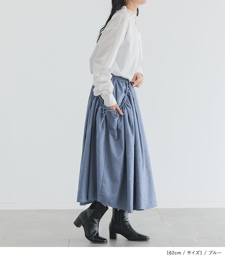 くすみブルーの花柄シャーリングフレアスカートに白のボウタイブラウスを合わせた、上品で爽やかな大人のキレイめ春コーディネート。