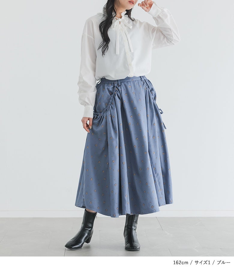ブルーの花柄シャーリングスカートに白の落ち感ブラウスをあわせた洗練スタイル。休日のお出かけやランチ会に映えるフェミニンな一着です。
