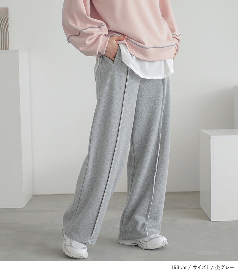 杢グレーのストレートワイドスウェットパンツ。表に出した縫い代の切り替えラインがストリートライクなこなれ感を演出し、スニーカーと合わせたこなれた足元を完成させます。