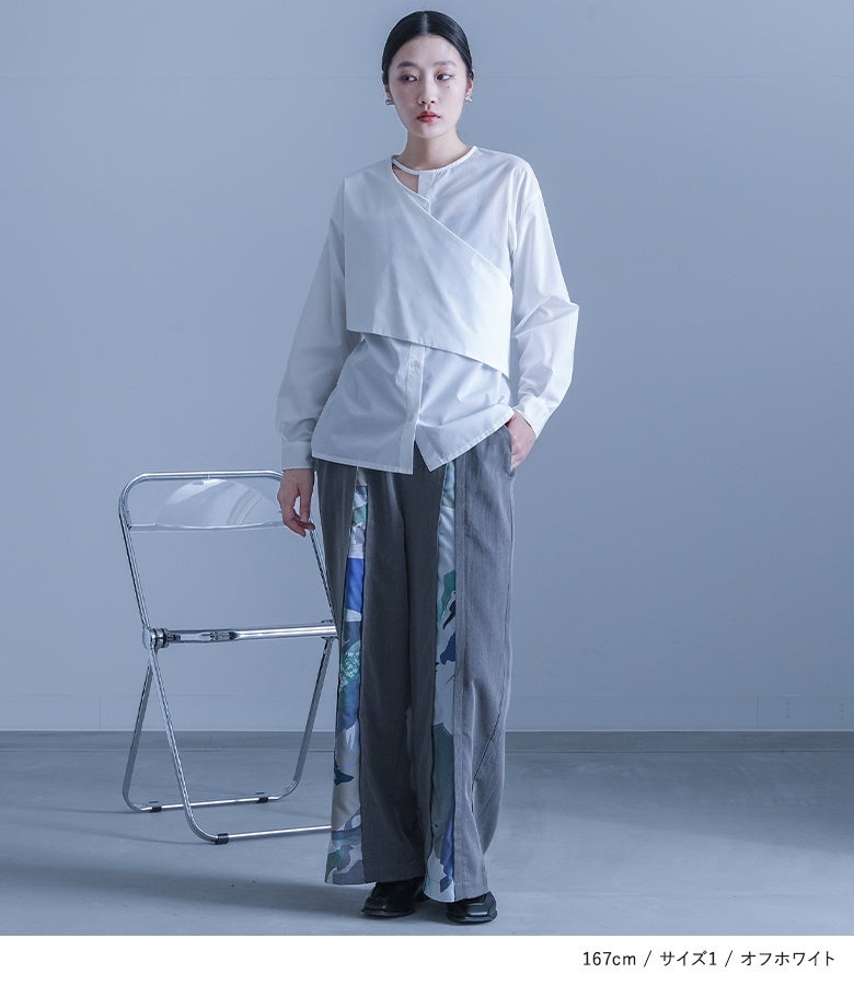 オフホワイトのカシュクールデザインシャツにグレーの柄切り替えパンツをあわせた着こなし。爽やかな白の重なりパーツが、全体を洗練されたクリーンな佇まいへ導きます。