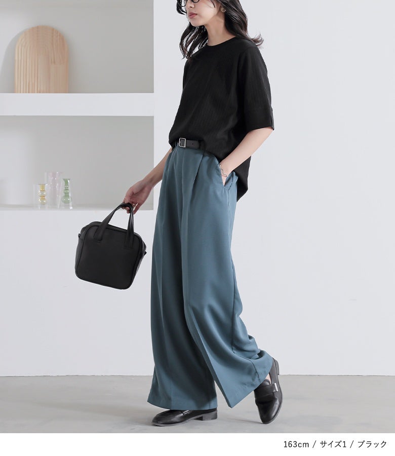 ブラックのシンプルリブカットソー。黒の半袖Tシャツをブルーのワイドパンツにタックインし、黒のレザーハンドバッグとローファーを合わせたお洒落な着こなし。正面から側面へ流れる綺麗なドレープシルエット。