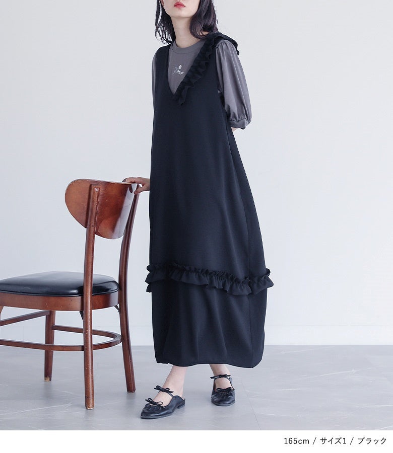 ブラックのアシメフリルジャンパースカート。広がりすぎないロング丈のゆったりフォルムと裾のギャザーフリルが、体型をカバーしながらスタイルアップされた立ち姿へ導きます。