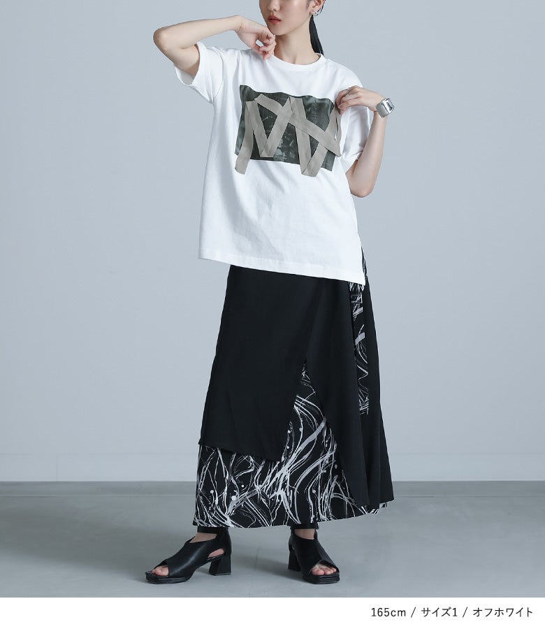 オフホワイトのテープデザイン半袖Tシャツにブラックの変形スカートを合わせた、モノトーンでまとめた洗練された大人のお出かけスタイル。デザイン性の高さが引き立つおしゃれな夏のレディースコーデです。