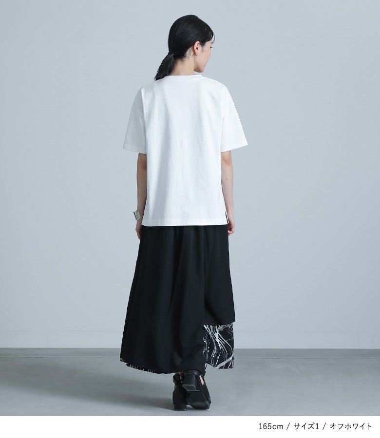 クリーンなオフホワイトの半袖Tシャツにブラックのロングスカートを合わせた、後ろ姿まで抜かりないモノトーンコーディネート。シンプルでありながらディテールにこだわった大人のリラックススタイルです。