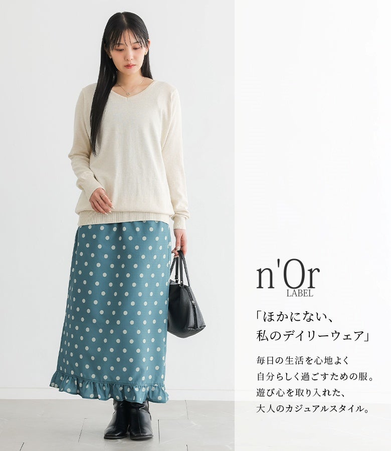 グリーンのミニフリルドットナロースカートにアイボリーのVネックニットをあわせたきれいめスタイル。遊び心を取り入れたドット柄と品のあるシルエットが、日常に心地よさを届けます。