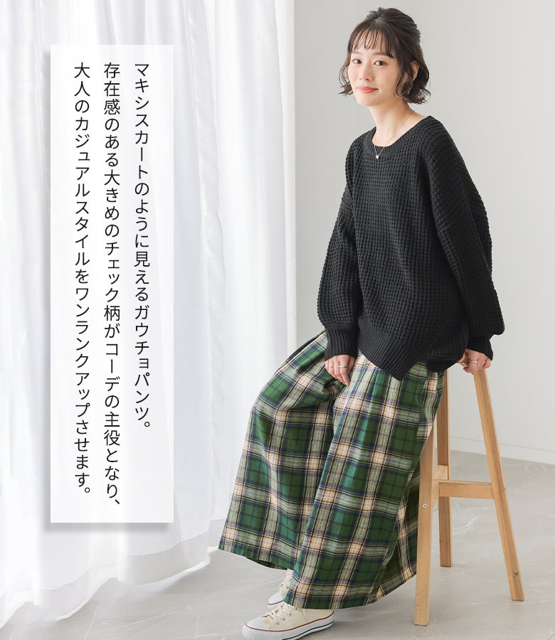 グリーンの大きめチェック柄ガウチョパンツに黒のワッフルニットとスニーカーをあわせた、休日のお出かけや行楽にぴったりの大人カジュアルスタイル。