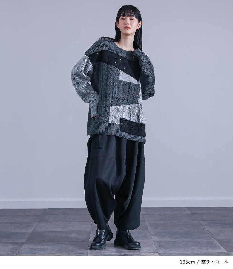 様々なパッチワーク編みが引き立つ杢チャコールのニットに黒ボトムスを合わせた大人シックコーデ。個性を引き立てるデザイン性で、秋冬の旅行や街歩きシーンを洗練されたスタイルに導きます。