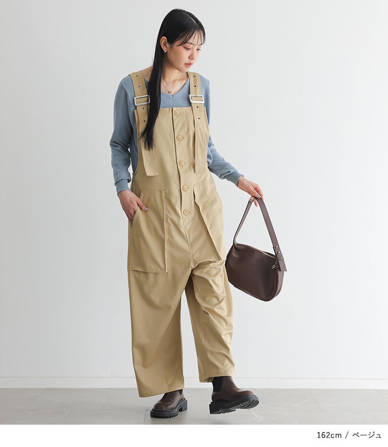 ベージュのサルエルサロペットに淡いブルーのVネックニットとブラウンブーツを合わせた大人の着こなし。リラックス感のあるワイドシルエットで、秋の休日ショッピングや旅行に最適です。