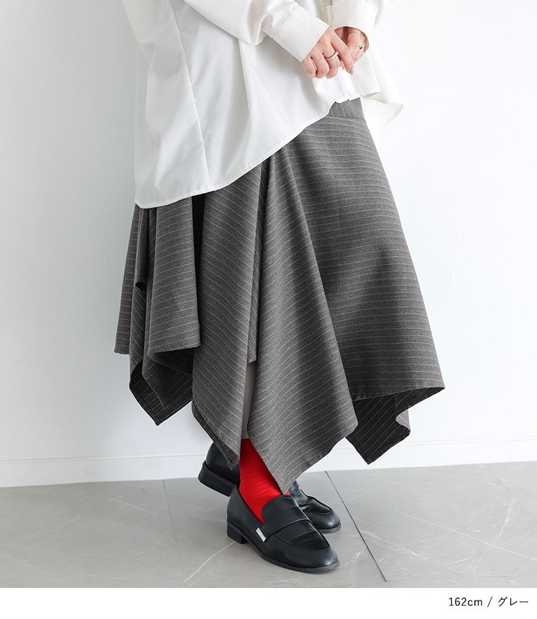 グレーのストライプ柄アシメフレアスカート。表情豊かなアシンメトリーヘムに鮮やかな赤ソックスを覗かせた、遊び心溢れる大人の足元コーディネートです。