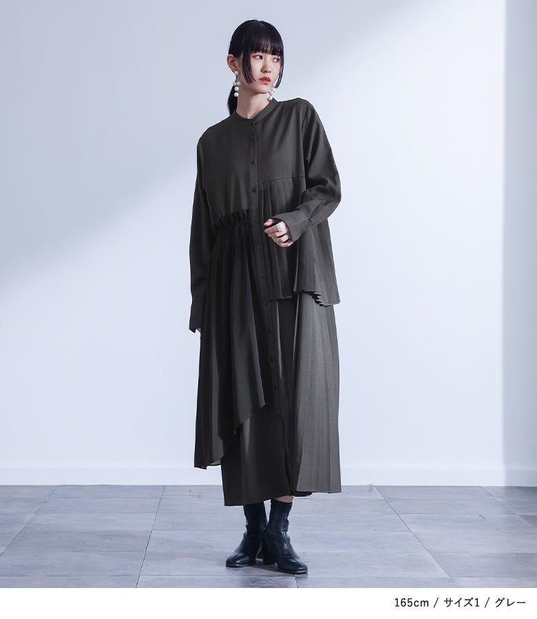 グレーのアシンメトリープリーツ長袖ワンピースに黒のショートブーツを合わせた、一枚で装いが決まる大人のモダンモードスタイル。
