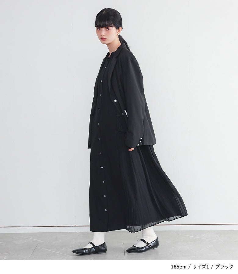ブラックのサイドプリーツフリルシャツワンピースにジャケットを羽織ったシックな着こなし。流れるような縦ラインとサイドのシフォンプリーツが、洗練された大人のモードスタイルを演出します。