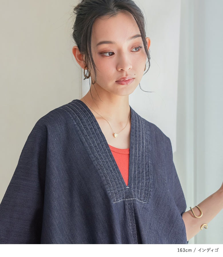 インディゴカラーのデニムカフタンワンピースの胸元から赤のインナーをチラ見せさせた、大人カジュアルな夏のデイリースタイル。