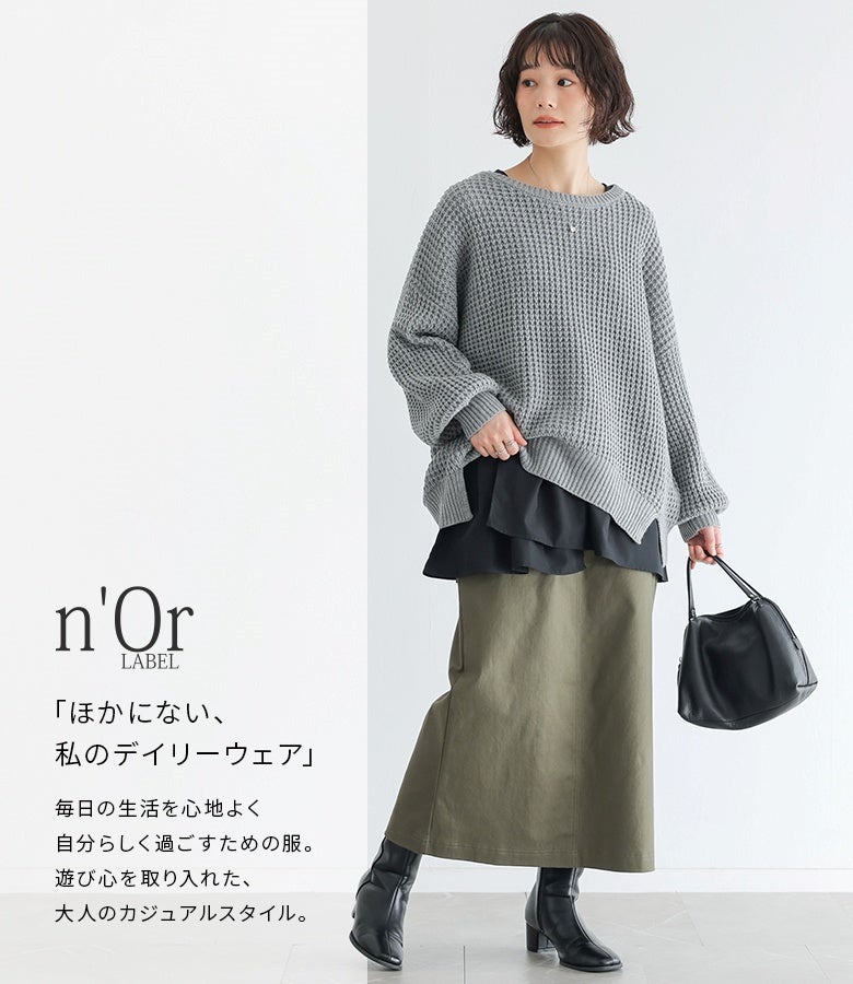 グレーのワッフルニットにブラックのレイヤードタンク、カーキのロングスカートを合わせた大人のモードカジュアル。裾から覗くブラックの布帛生地が全体を引き締め、都会的でメリハリのあるレイヤードスタイルを叶えます。