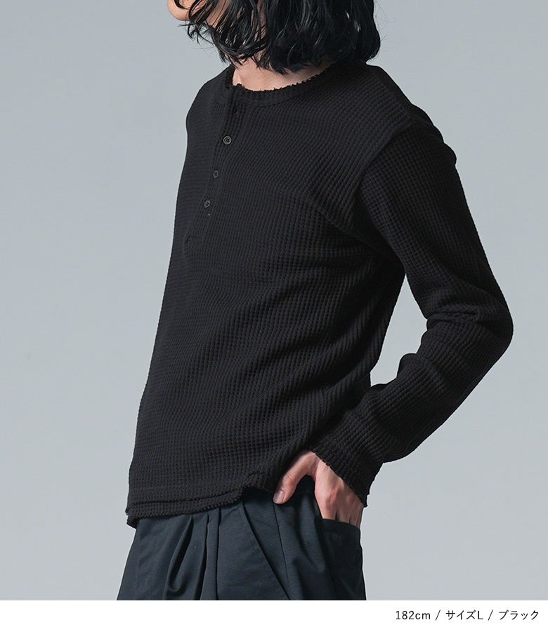 コットン100%の柔らかな風合いが魅力的なブラックの長袖ワッフルTシャツ。すっきりとしたヘンリーネックと首元のカットオフ加工が、シックな着こなしに程よい抜け感をプラスします。