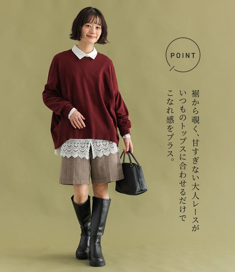 ボルドーのニットの下にオフホワイトの裾レースシャツを重ね、ショートパンツとロングブーツを合わせたきれいめトラッドスタイル。ニットの裾から覗く大人の裾レースが、シンプルな重ね着にこなれ感を与えます。