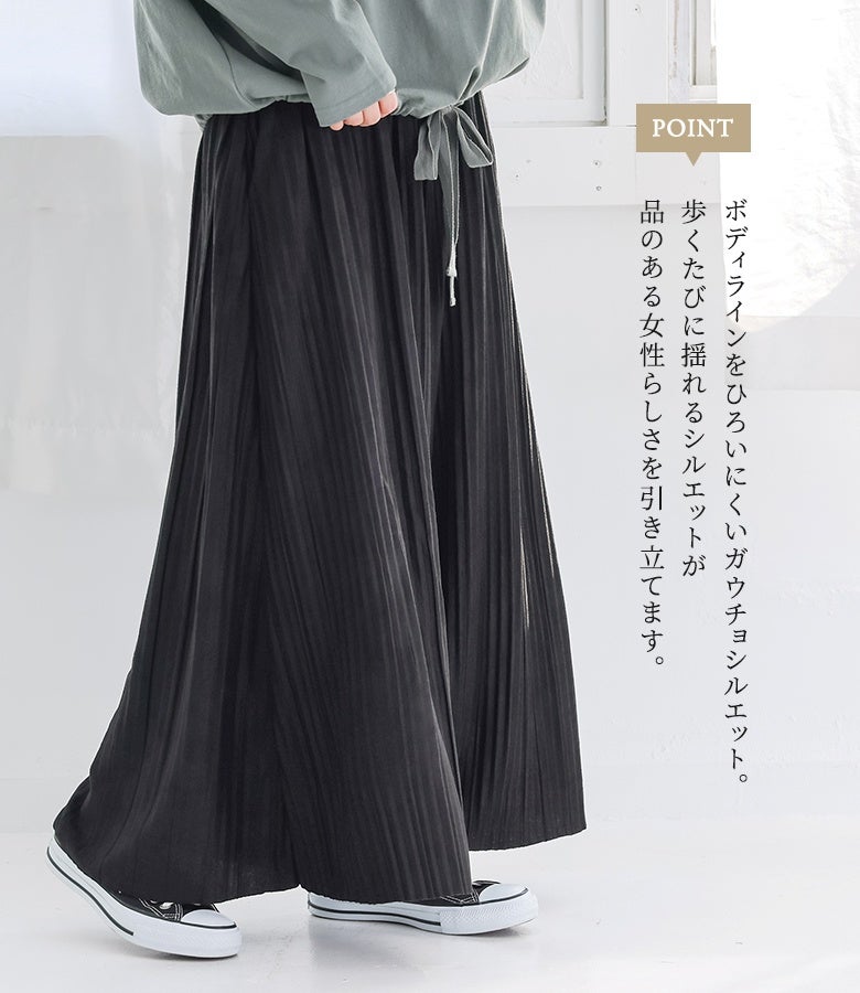 ブラックのプリーツガウチョパンツにカーキのトップスとスニーカーを合わせた、デイリー使いにおすすめの大人カジュアルコーデ。歩くたびに揺れるシルエットが