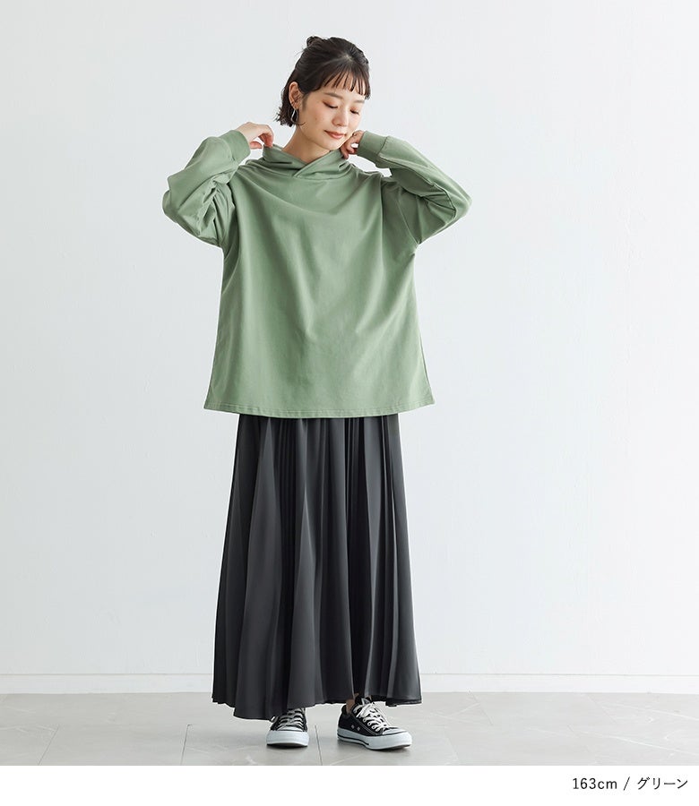 グリーンのフーディーネックカットソーに、黒のプリーツスカートとスニーカーを合わせた、秋の行楽やデイリーユースにおすすめのリラックスコーデ。