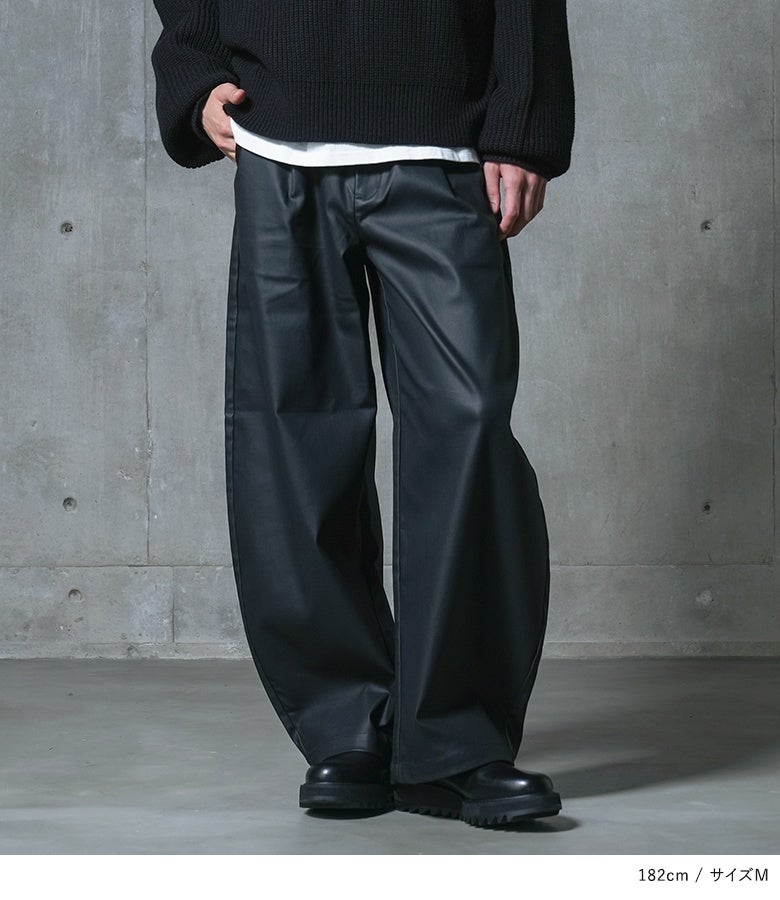 ブラックのフェイクレザーバレルパンツ。タック入りの腰周りから裾へ向かって丸みを帯びるシルエットが脚ラインを拾わず、スタイルアップとこなれ感を同時に演出します。