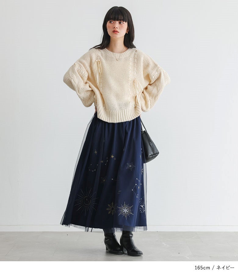 ネイビーの星柄刺繍チュールスカートにアイボリーのケーブルニットと黒ブーツを合わせた、上品で華やかな冬のデートスタイル。