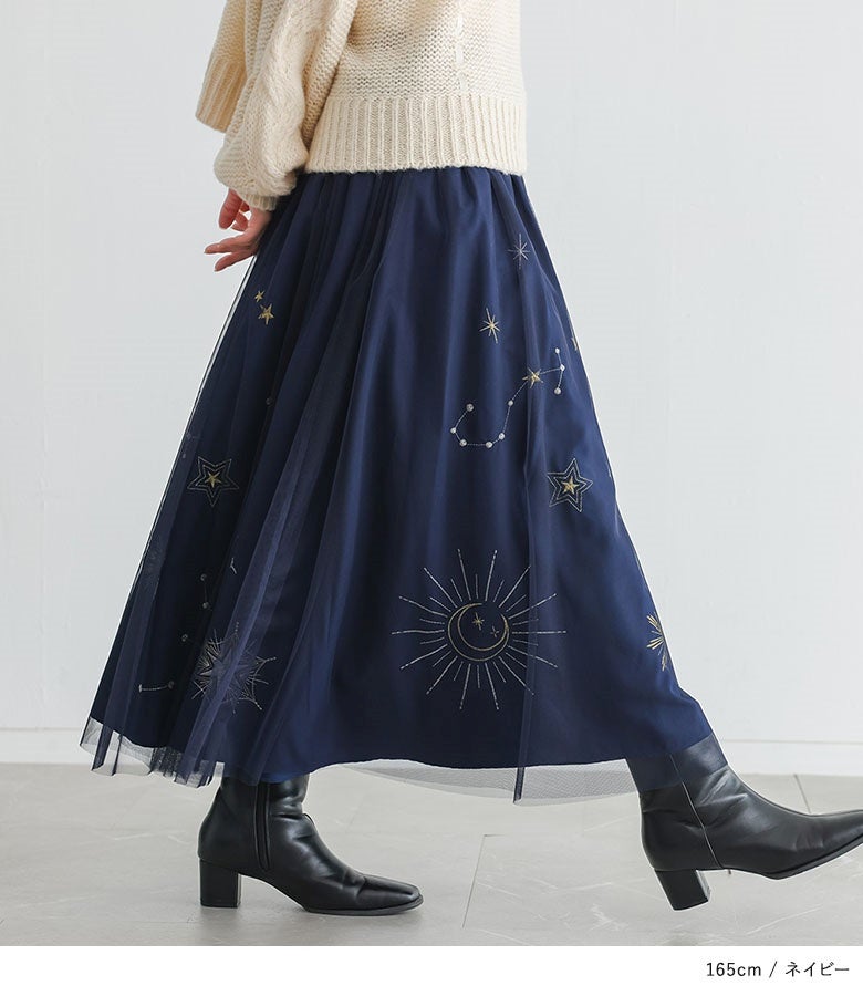動きに合わせてチュールから透ける星柄刺繍が煌めく、ネイビーチュールスカートと黒のショートブーツを合わせた洗練された大人スタイル。